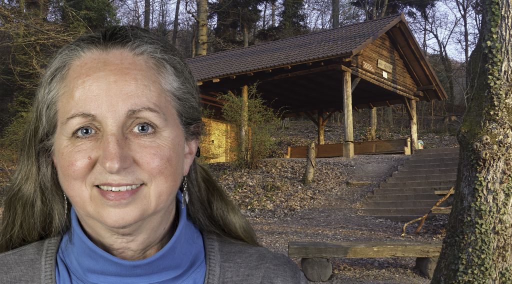 Foto-Collage: Frau mit langen, grauen Haaren, im Hintergrund offene Waldhütte
